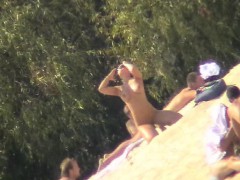 Uninhibited nudists soak up some sun on the beach on a hot
